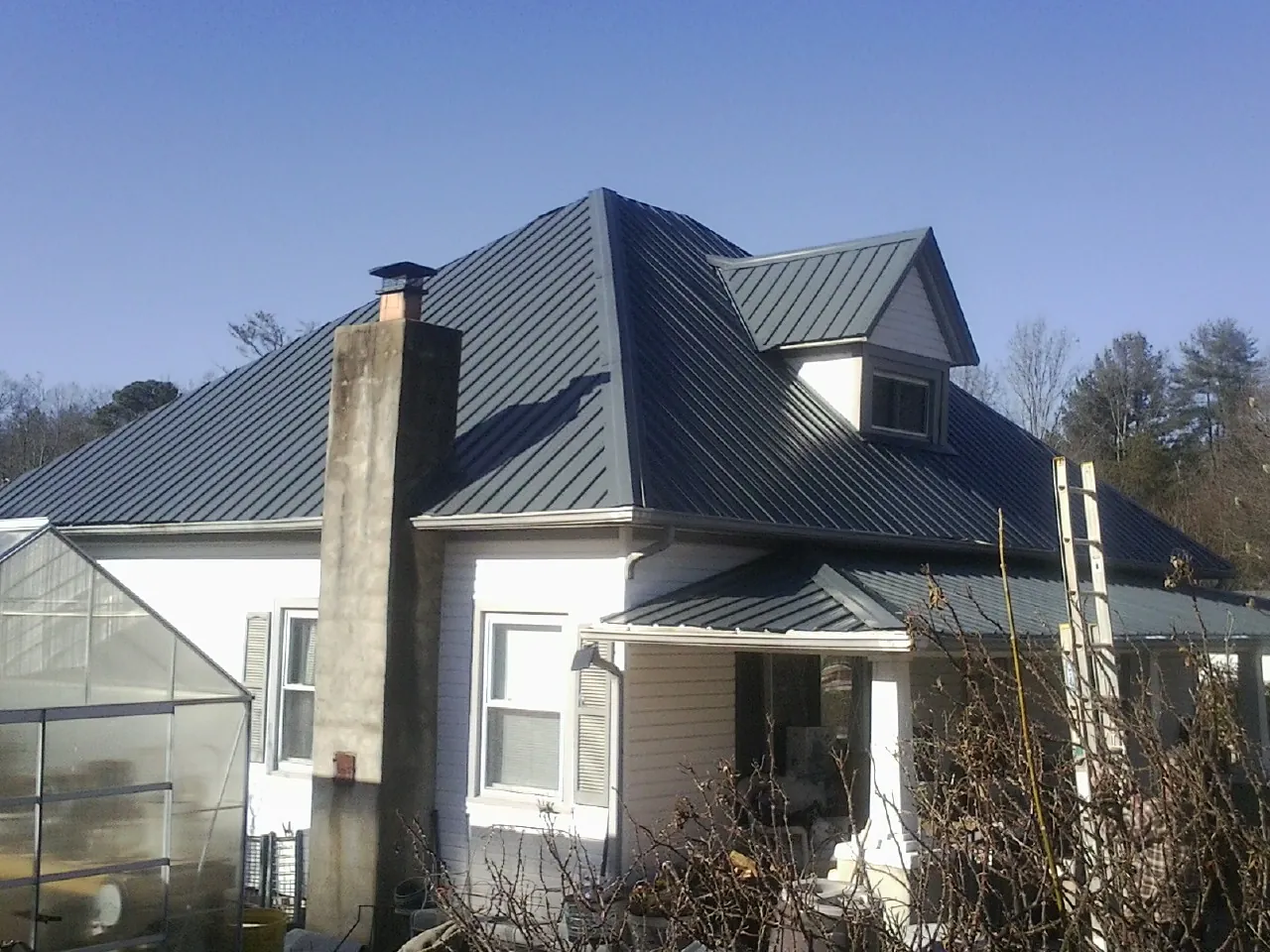 Dark blue standing seam metal roof on a white farmhouse with dormer — Slate & Tile Roof Repair by Roofing Brothers in Netcong