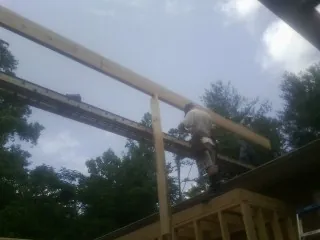 Carpenter setting a ridge beam over a new addition frame — Ice Dam Removal by Roofing Brothers in Netcong