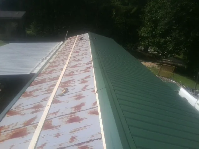 Old rusted panels beside newly installed green metal roofing — Wind Damage Roof Repair by Roofing Brothers in Netcong