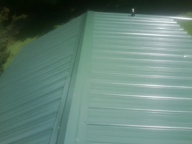 New green metal panels meeting at the ridge of a roof — Flat Roof Repair work by our crew in Netcong