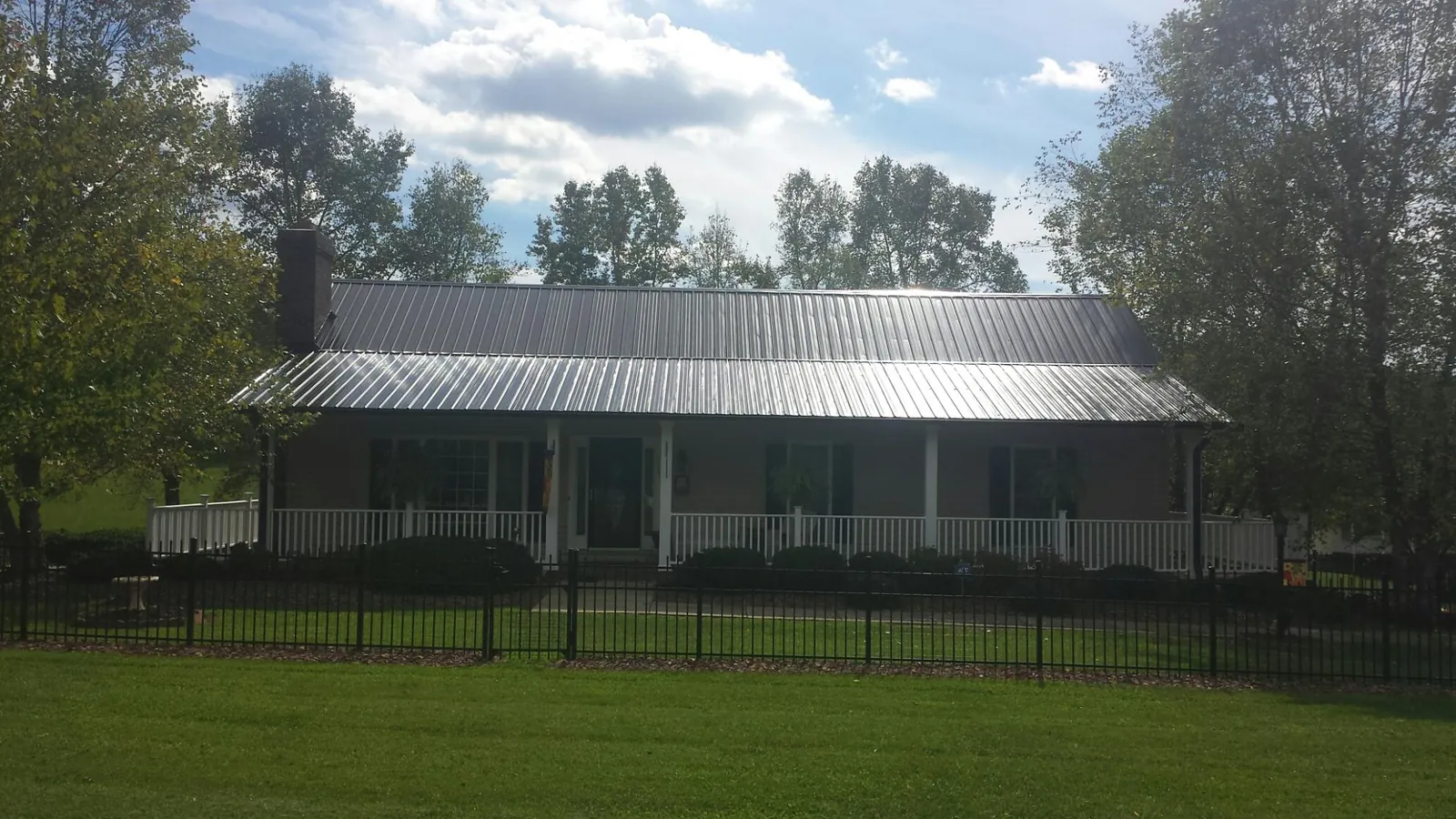 Gray metal roof on a brick ranch with a full width front porch — Gutter Guard Installation work by our crew in Netcong