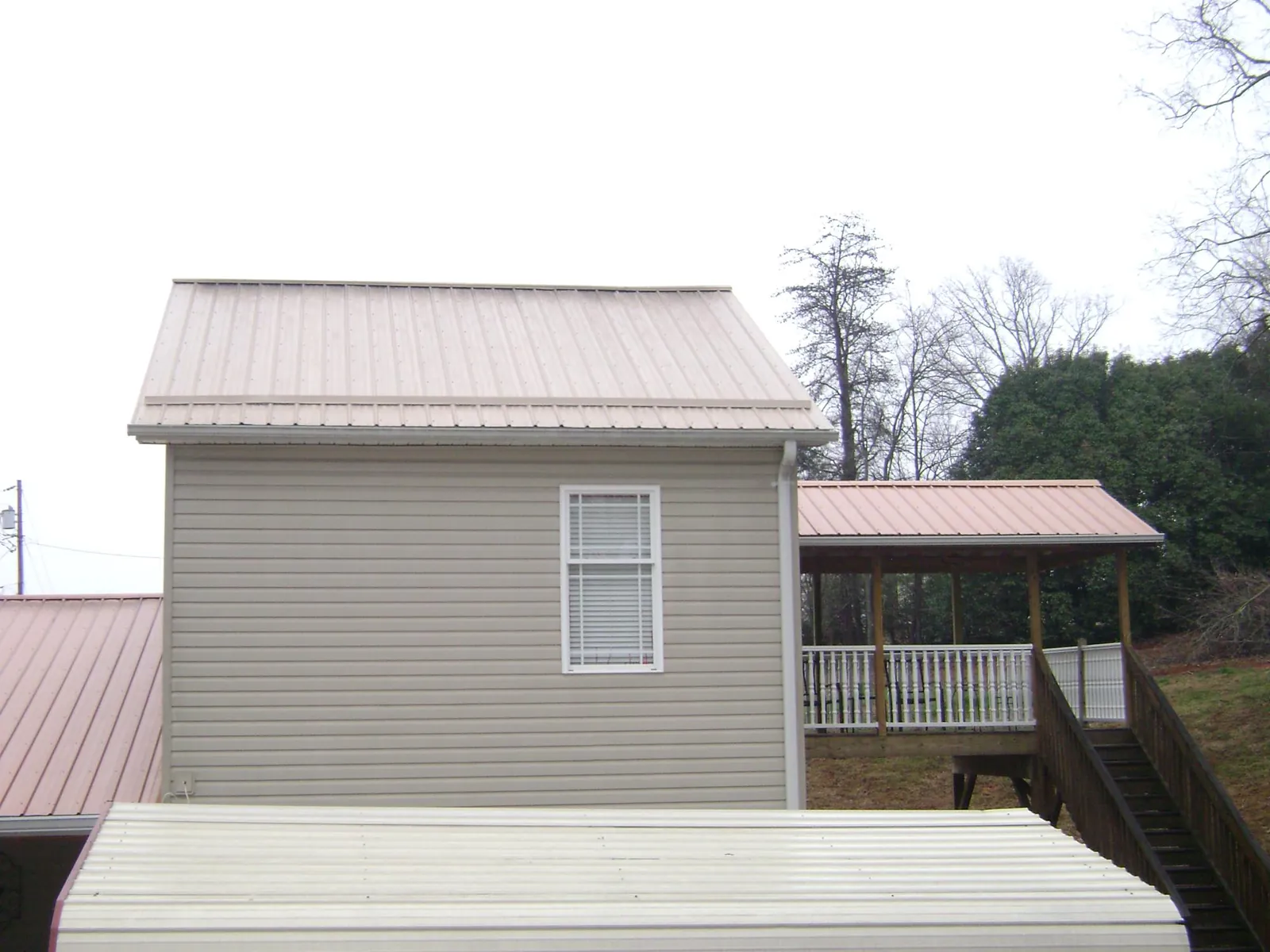 Tan metal roofs on a two story addition and attached porch, from a Roof Replacement job in Netcong
