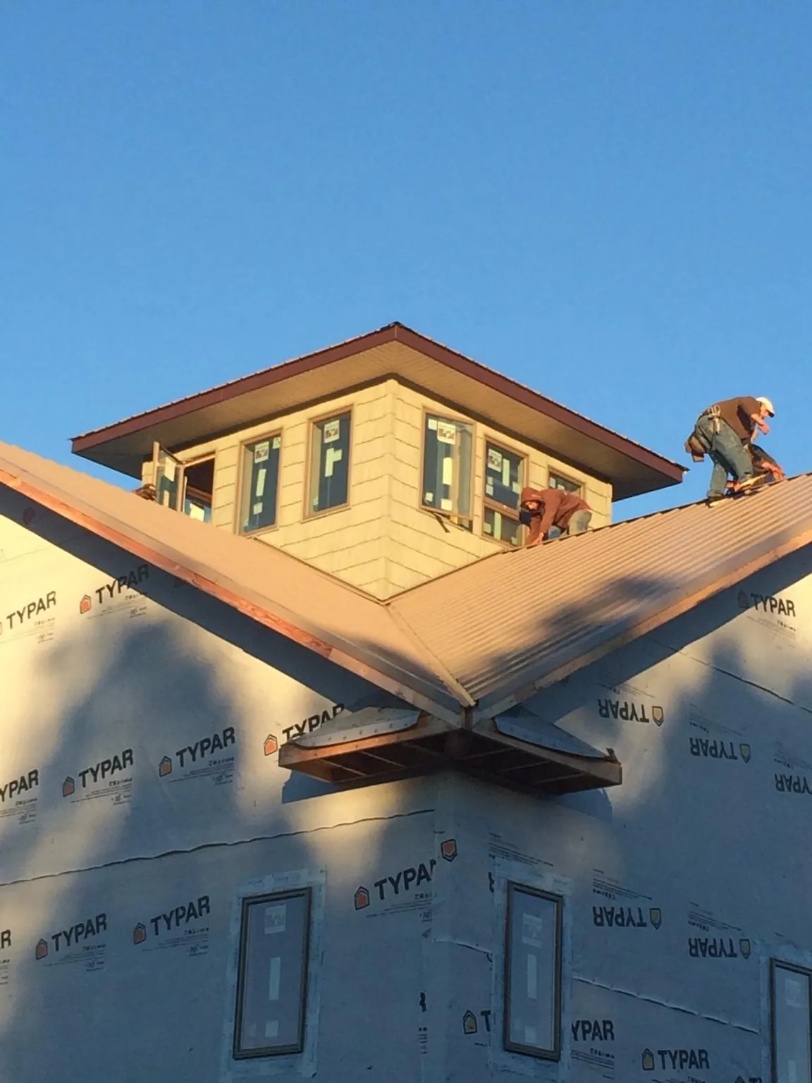 Roofers working around a rooftop cupola on a new metal roof at sunset — Roof Waterproofing in Netcong by Roofing Brothers
